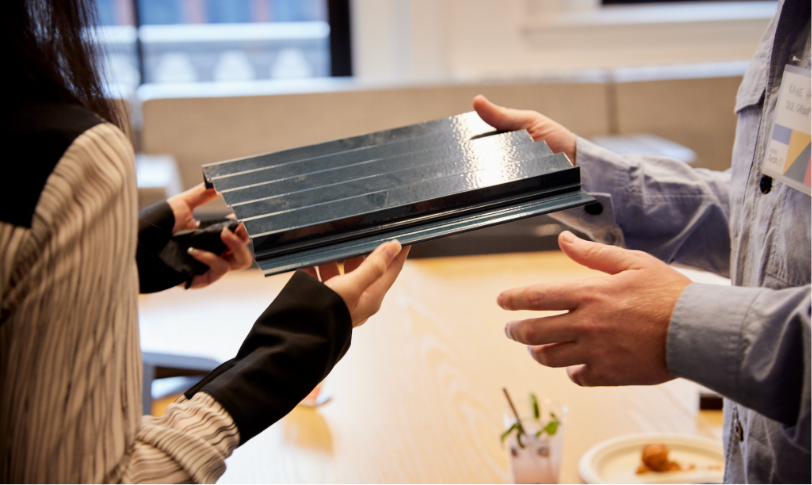 Individuals examining and passing around stacked material samples during a meeting. Individuals examining and passing around stacked material samples during a meeting.