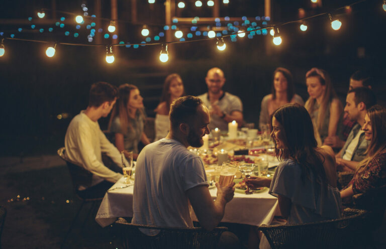 people gathered for dinner outdoors under string lights